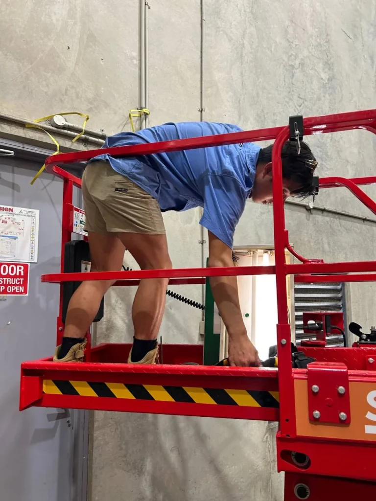 Aaron from Amplus Electrical and Air working at height in a commercial warehouse — licensed electrician Capalaba and Brisbane Bayside