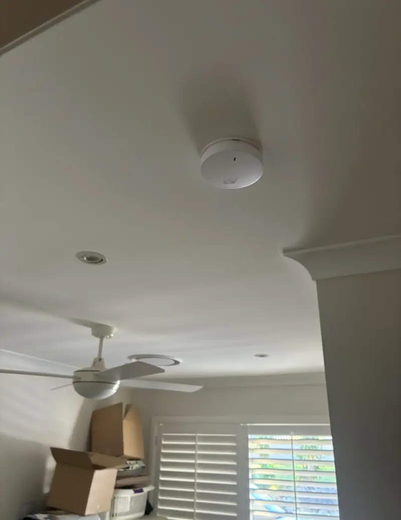 Smoke alarm installed on bedroom ceiling in a Brisbane home — every bedroom requires a compliant alarm