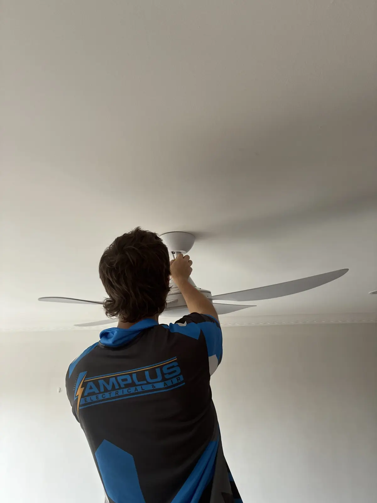 Amplus electrician Aaron installing a ceiling fan in a Redlands home