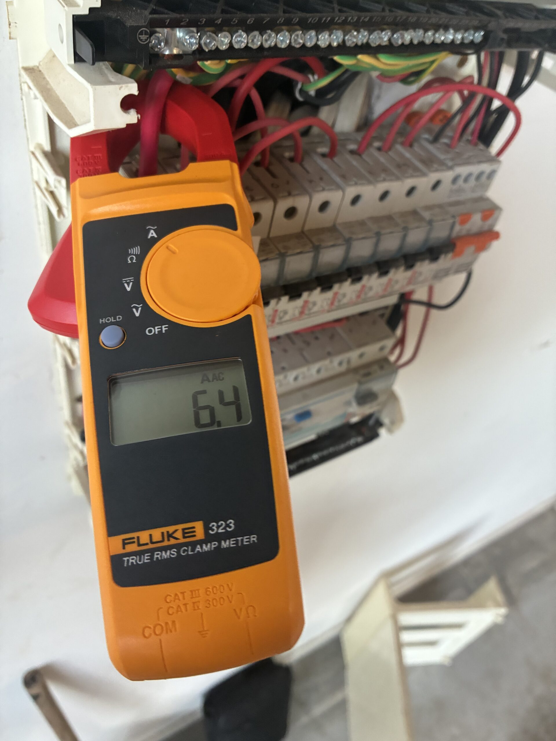 Electrician using multimeter to test switchboard voltage during upgrade in Brisbane home