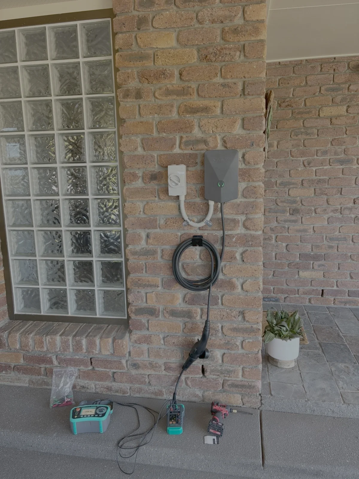Evnex EV charger mounted on a brick wall exterior in Brisbane