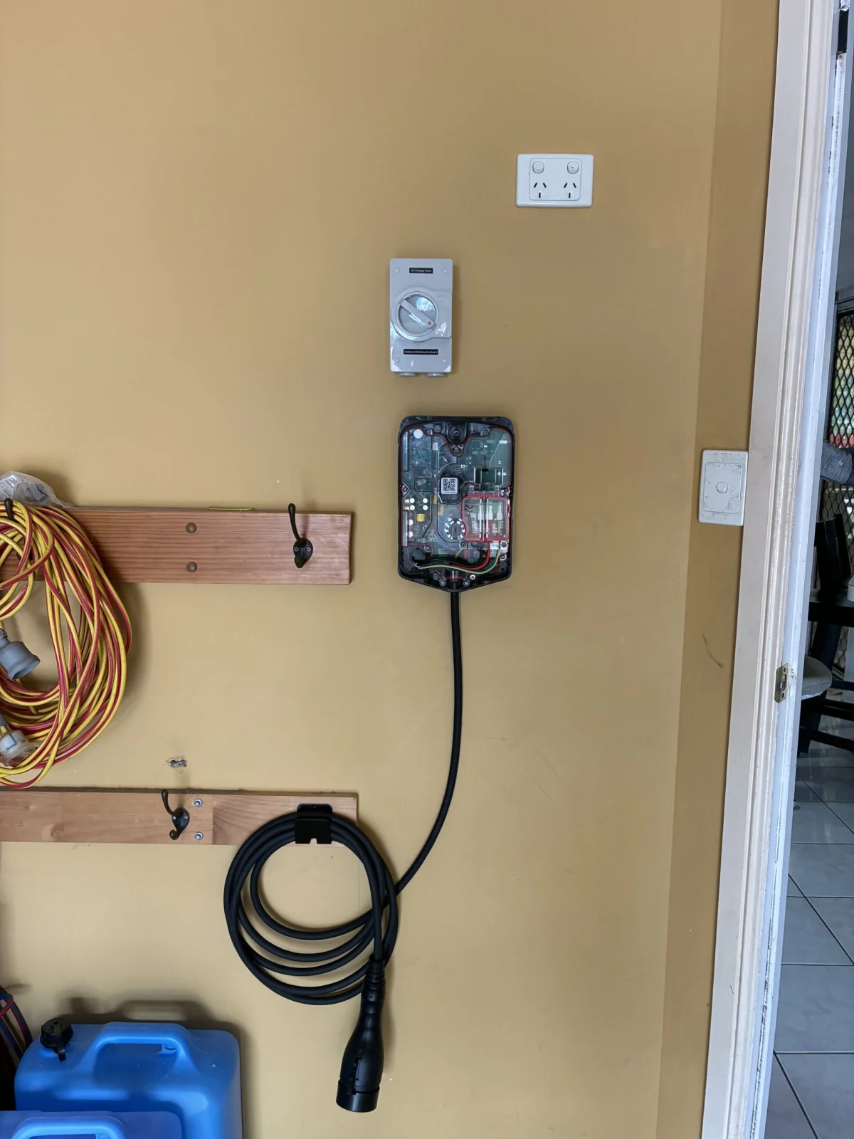 Evnex EV charger installed in a garage with the internal cover removed showing the wiring