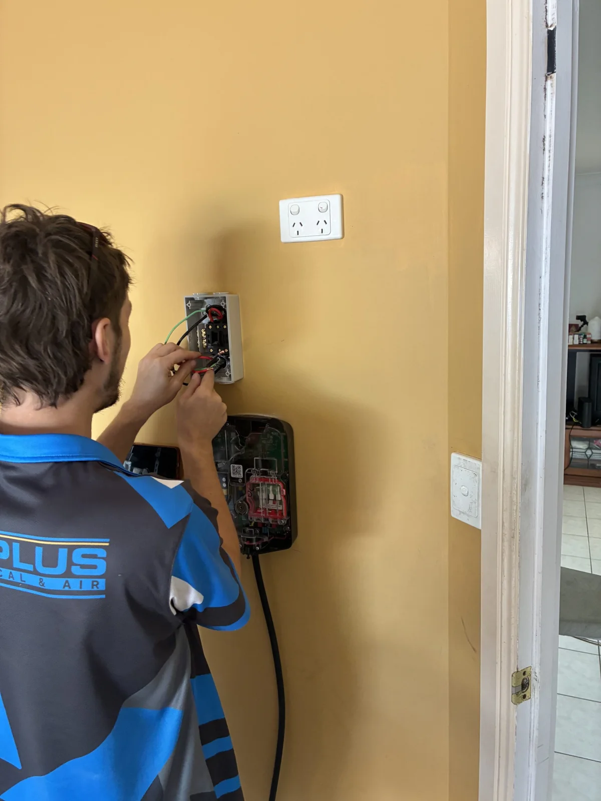 Mitch installing an Evnex EV charger on a garage wall in Brisbane